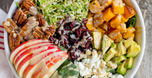 An image of prepared Autumn Salad with Dairy-Free Tahini Hemp Dressing made with butternut squash, Pacific Foods® Hemp Unsweetened Original Beverage, tahini, spinach. Brussels sprouts, apple, avocado, feta, cranberries and pecans.