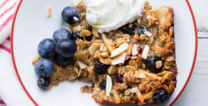 An image of prepared Baked Coconut and Blueberry Oatmeal made with coconut, oats, almonds, dried blueberries, maple syrup, Pacific Foods® Organic Oat Original Beverage, blueberries and yogurt.