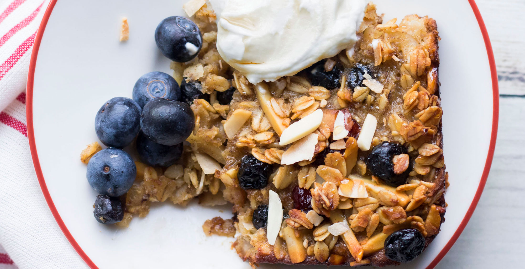 An image of prepared Baked Coconut and Blueberry Oatmeal made with coconut, oats, almonds, dried blueberries, maple syrup, Pacific Foods® Organic Oat Original Beverage, blueberries and yogurt.