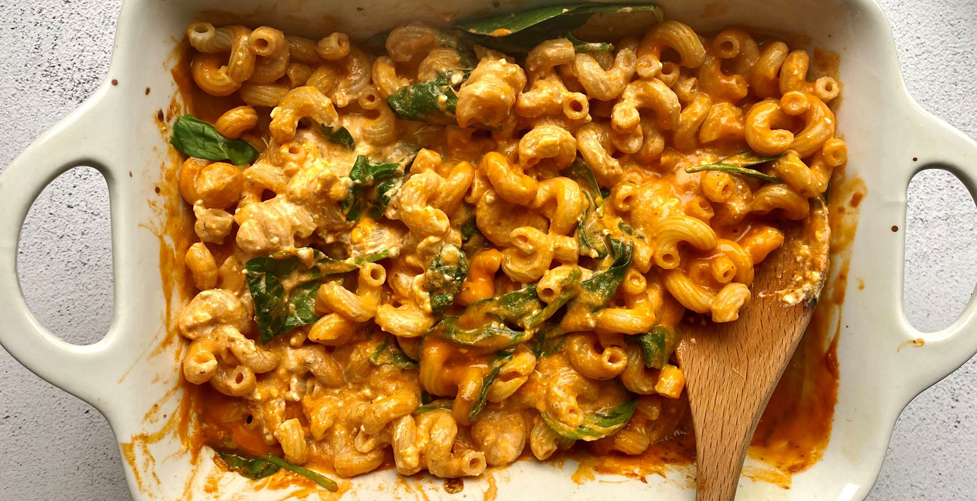 An image of prepared Baked Feta Pasta with Organic Creamy Tomato Basil Soup made with cavatappi pasta, Pacific Foods™ Organic Vegan Creamy Tomato Basil Soup, feta cheese, oregano and baby spinach.