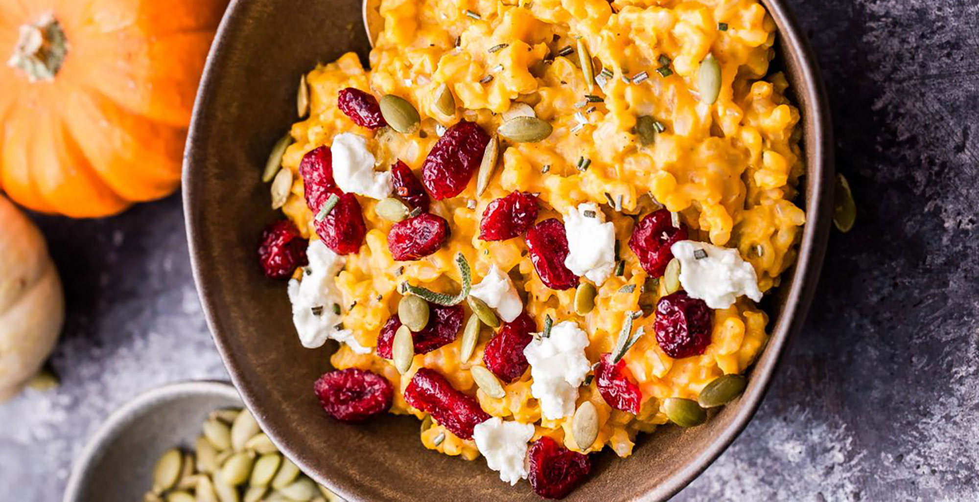 An image of prepared Baked Pumpkin Goat Cheese Risotto made with Pacific Foods® Organic Low Sodium Vegetable Broth , pumpkin puree, brown rice, sage, rosemary, white wine, goat cheese, cranberries and pumpkin seeds.