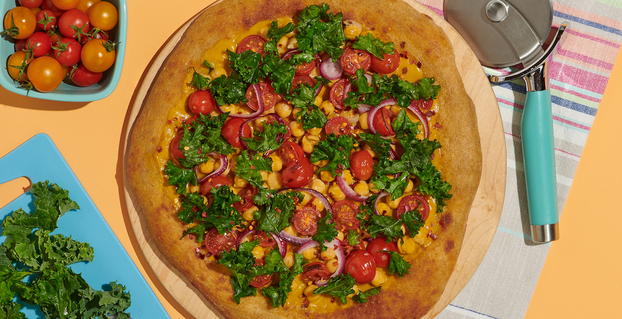 An image of prepared Butternut Squash Pizza with Kale made with Pacific Foods® Organic Cream Butternut Squash Soup, chickpeas, red onion, cherry tomatoes, kale and whole grain pizza dough.