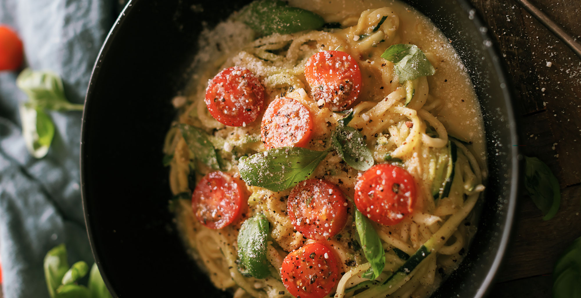 An image of prepared Carrot Ginger Cashew Alfredo Sauce for Zoodles made with Pacific Foods® Organic Almond Original Beverage, Pacific Foods® Organic Cashew Carrot Ginger Soup, zucchini noodles, cherry tomatoes and basil.