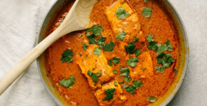 An image of prepared Chili Lime Poached Salmon made with salmon, Pacific Foods® Organic Low Sodium Vegetable Broth, coconut milk, lime juice and lime.