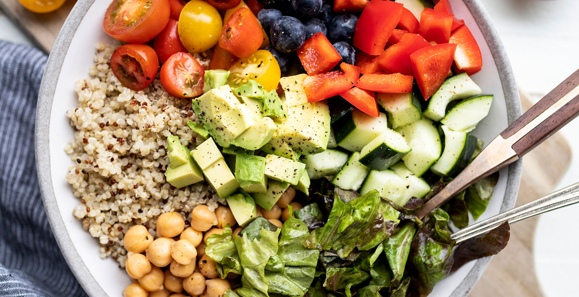 An image of prepared Chopped Summer Salad made with Pacific Foods® Organic Salted Chicken Bone Broth, quinoa, romaine, chickpeas, blueberries, cucumber, cherry tomatoes and avocado.