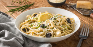 An image of prepared Creamy Mushroom-Artichoke Pasta made with linguine, Pacific Foods® Organic Cream of Mushroom Condensed Soup, artichoke hearts, black olives, chives and Parmesan cheese.