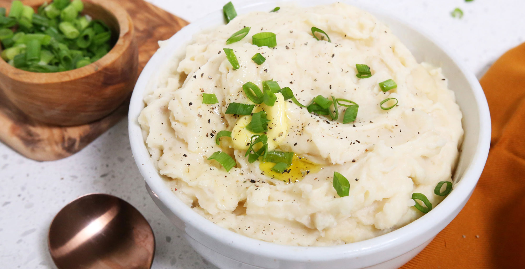 An image of prepared Crockpot Mashed Potatoes made with russet potatoes, Pacific Foods® Organic Turkey Broth, Pacific Foods® Organic Unsweetened Almond Original Beverage, butter and green onions.