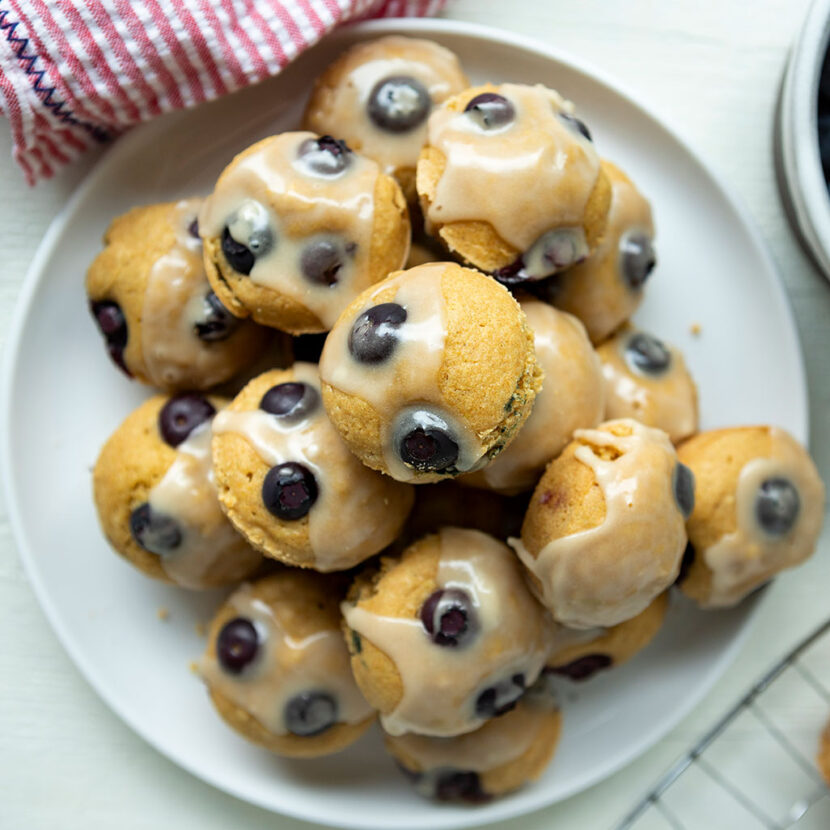 An image of prepared Dairy-Free Blueberry Mini Muffins with Maple Glaze made with Pacific Foods® Organic Oat Original Beverage, blueberries and maple syrup.
