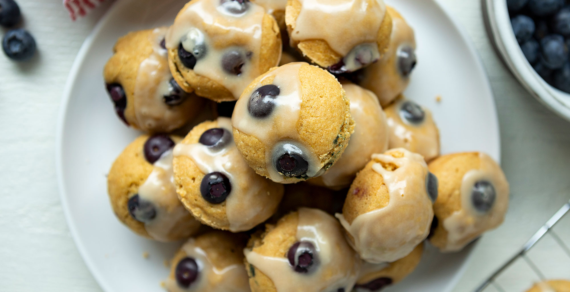 An image of prepared Dairy-Free Blueberry Mini Muffins with Maple Glaze made with Pacific Foods® Organic Oat Original Beverage, blueberries and maple syrup.