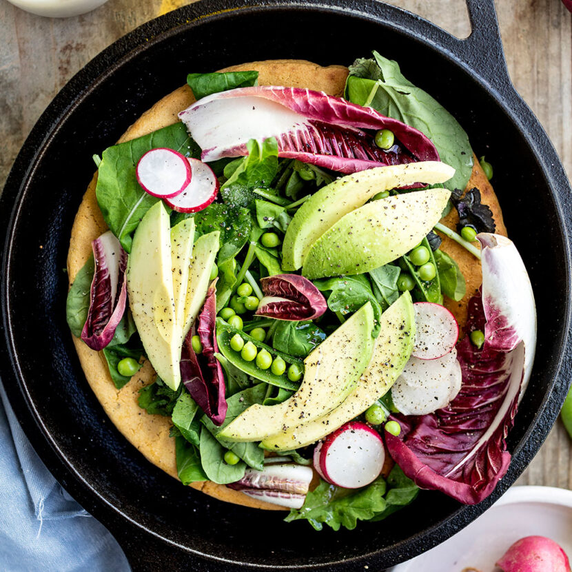 An image of prepared Gluten-Free Chickpea Flour Flatbread made with chickpea flour, Pacific Foods® Organic Vegetable Broth, mixed salad greens, avocado, green peas and radishes.