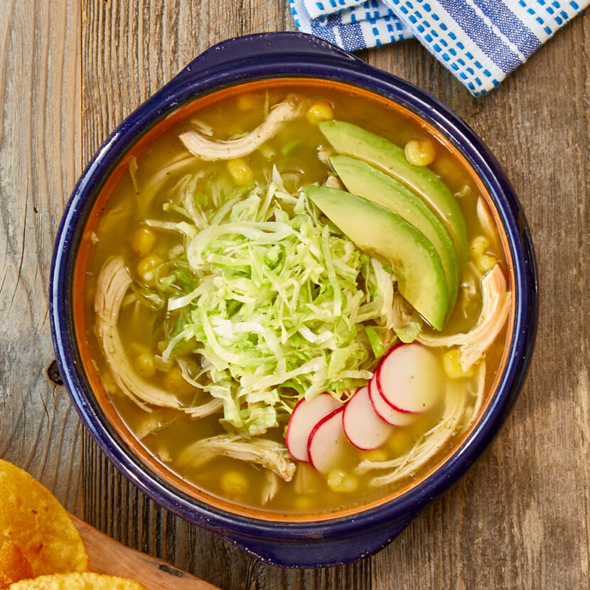 An image of prepared Instant Pot® Posole Verde made with tomatillos, garlic, Pacific Foods® Organic Free Range Low Sodium Chicken Broth, rotisserie chicken, hominy, avocado and radish.