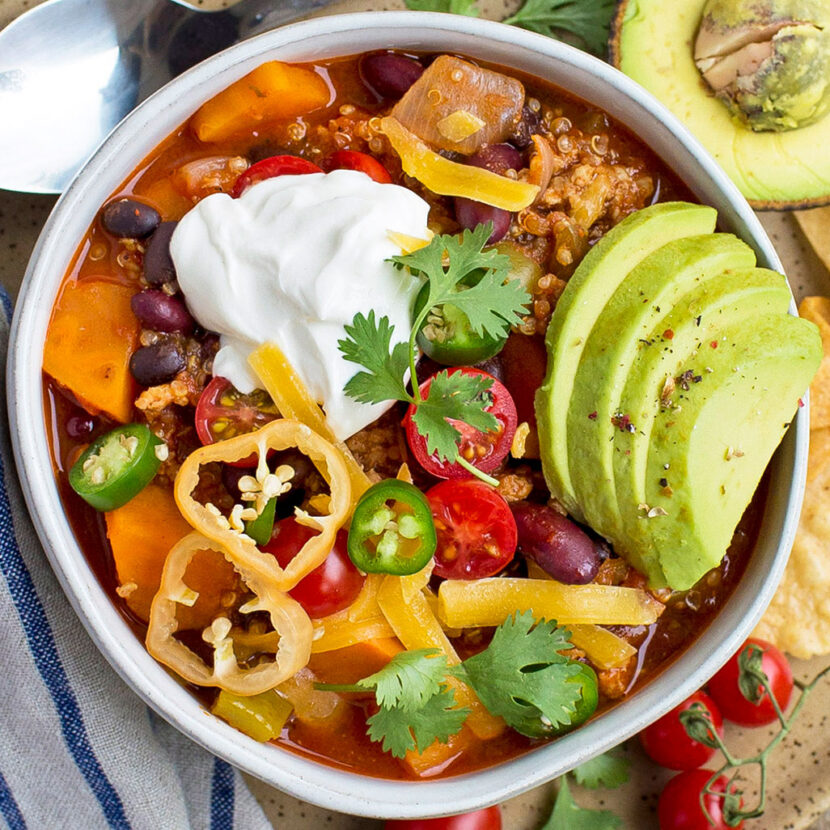 An image of prepared Instant Pot® Sweet Potato, Turkey and Quinoa Chili made with ground turkey, sweet potato, red pepper, tomatoes, black beans, kidney beans, quinoa, Pacific Foods® Organic Unsalted Chicken Bone Broth, Cheddar cheese and avocado.