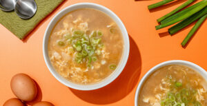 An image of prepared Keto Egg Drop Soup made with onion, Pacific Foods® Organic Unsalted Chicken Bone Broth, eggs and green onions.