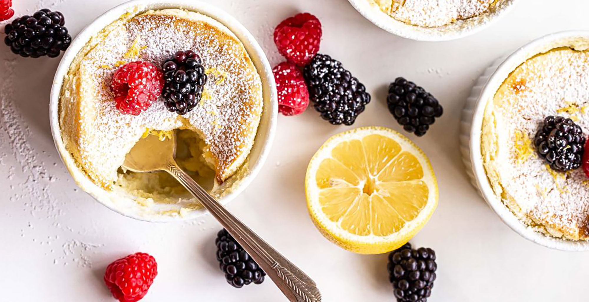 An image of prepared Lemon Pudding Cakes made with eggs, Pacific Foods® Organic Unsweetened Almond Original Beverage, lemon and mixed berries.