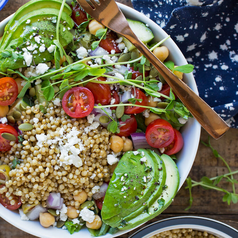 An image of prepared Mediterranean Sorghum Bone Broth Bowl made with sorghum, Pacific Foods® Unsalted Organic Chicken Bone Broth, spinach, chickpeas, cherry tomatoes, cucumber, red onion, feta cheese, avocado and olive oil.