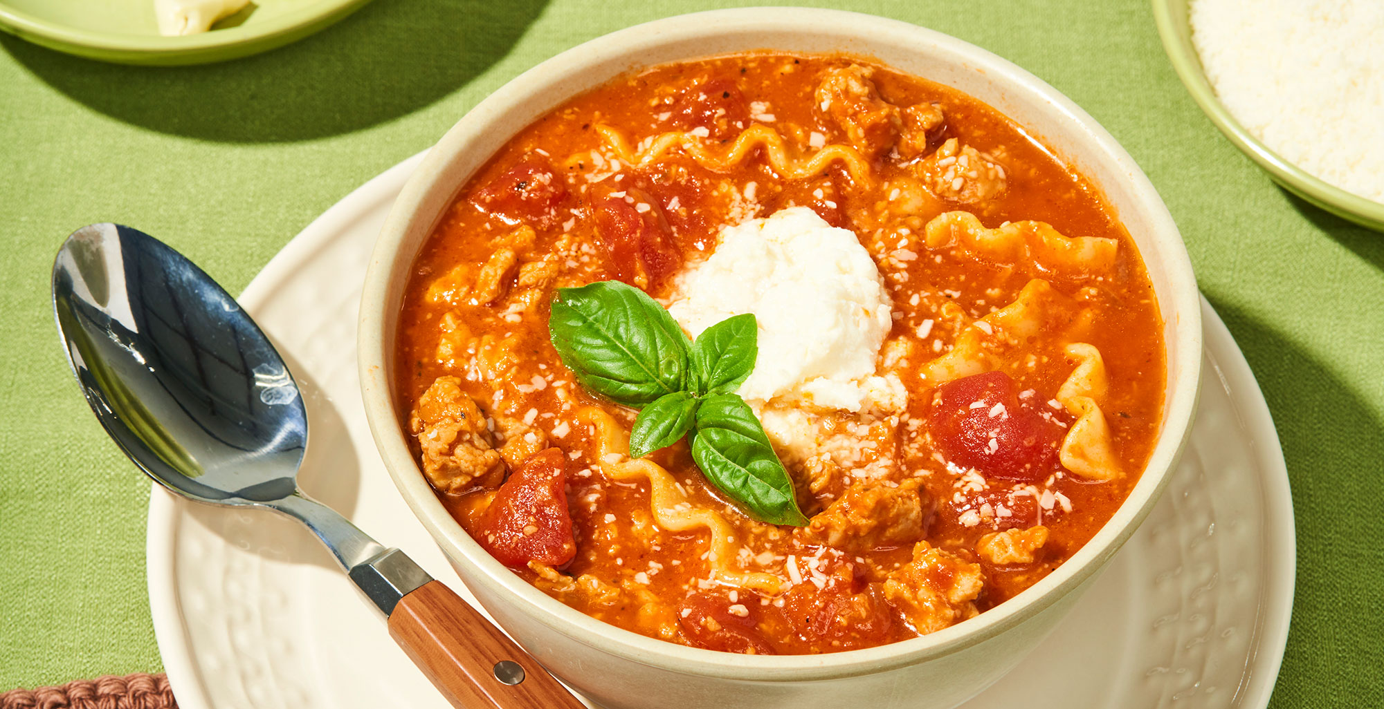 An image of prepared One-Pot Lasagna Soup made with Pacific Foods® Organic Vegetable Broth, Pacific Foods® Organic Creamy Tomato Basil Soup, pork sausage, tomatoes, lasagna noodles, Parmesan, mozzarella and ricotta cheese.