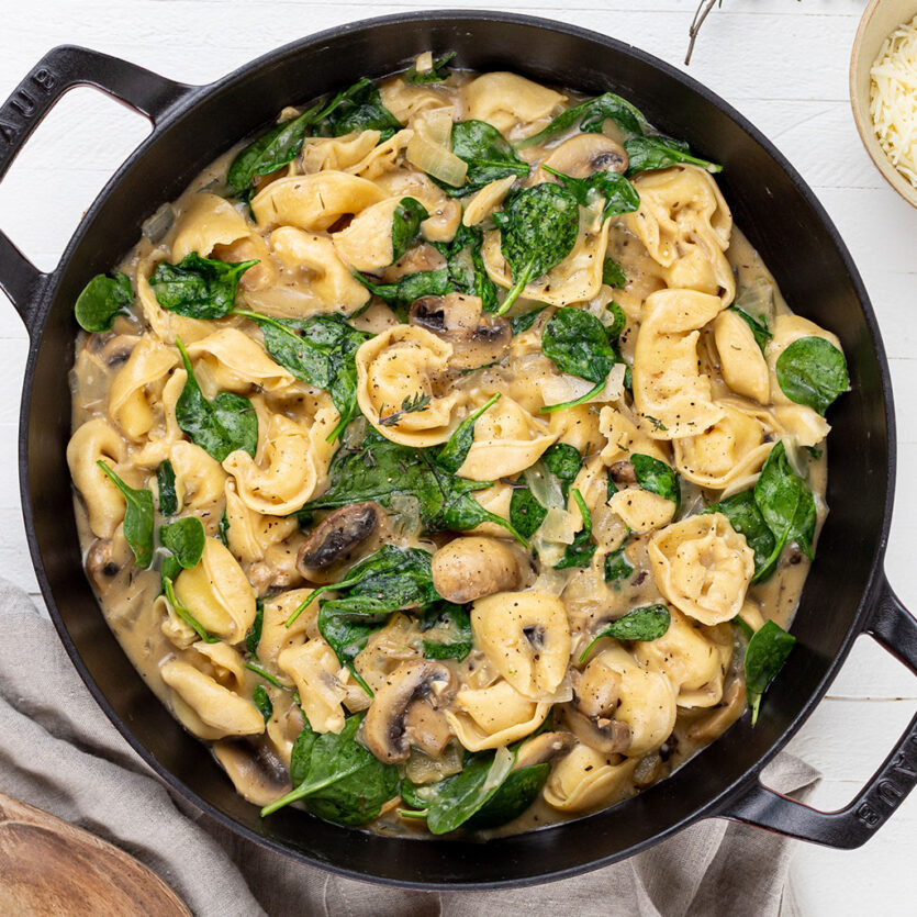 An image of prepared One-Pot Creamy Mushroom Tortellini made with mushrooms, thyme, Pacific Foods™ Organic Free Range Chicken Broth, Pacific Foods™ Organic Cream of Mushroom Condensed Soup, cream, tortellini, baby spinach and Parmesan.