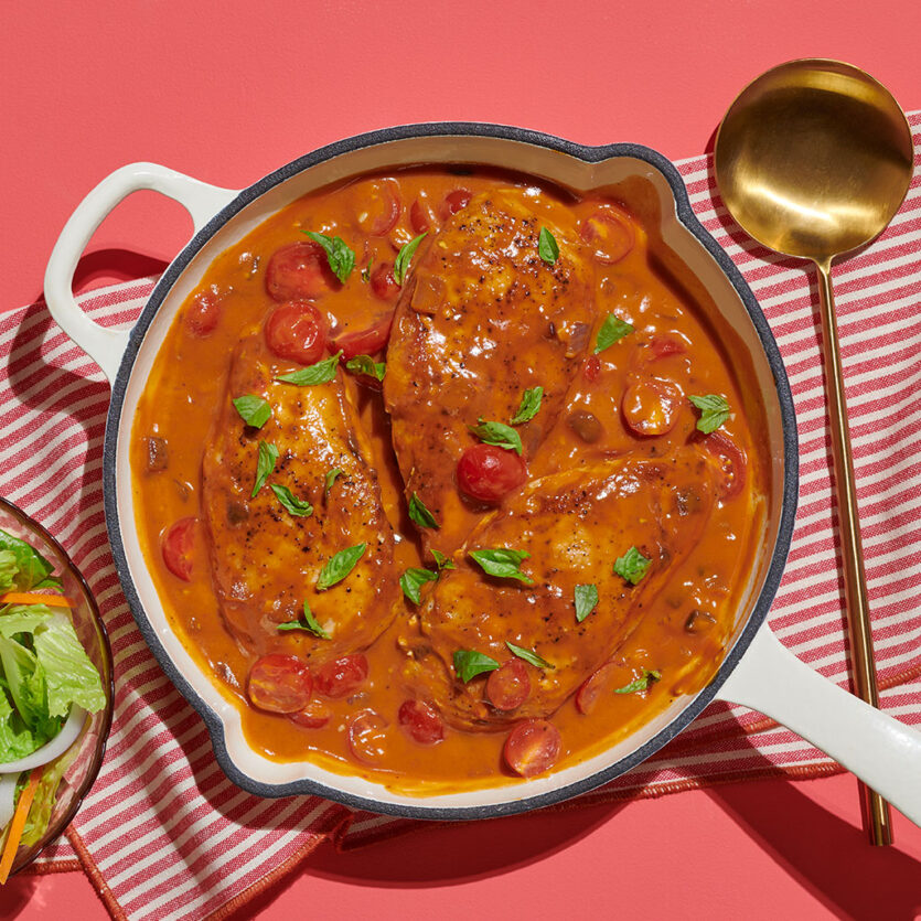 An image of prepared One-Skillet Roasted Red Pepper Chicken made with chicken, Pacific Foods® Organic Roasted Red Pepper & Tomato Soup, red onion, basil, olive oil and cherry tomatoes.