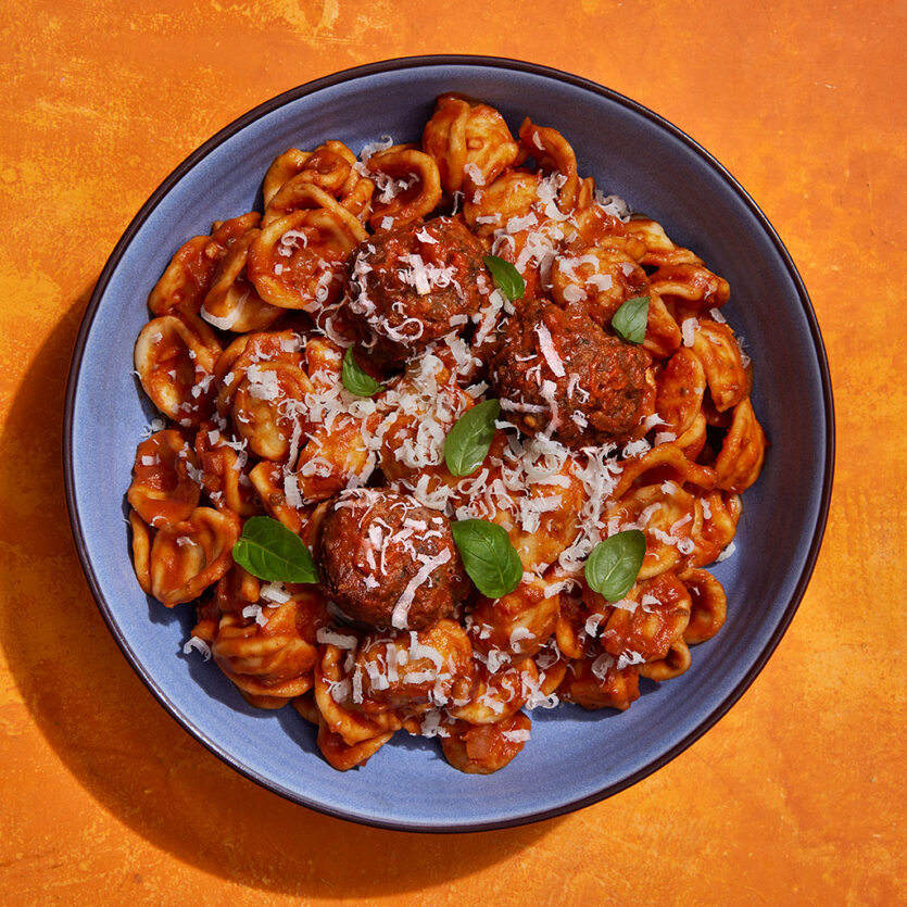An image of prepared Orecchiette with Roasted Red Pepper and Tomato Sauce made with Pacific Foods® Organic Roasted Red Pepper & Tomato Soup, onion, orecchiette pasta, Italian meatballs, basil and Parmesan.