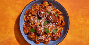 An image of prepared Orecchiette with Roasted Red Pepper and Tomato Sauce made with Pacific Foods® Organic Roasted Red Pepper & Tomato Soup, onion, orecchiette pasta, Italian meatballs, basil and Parmesan.