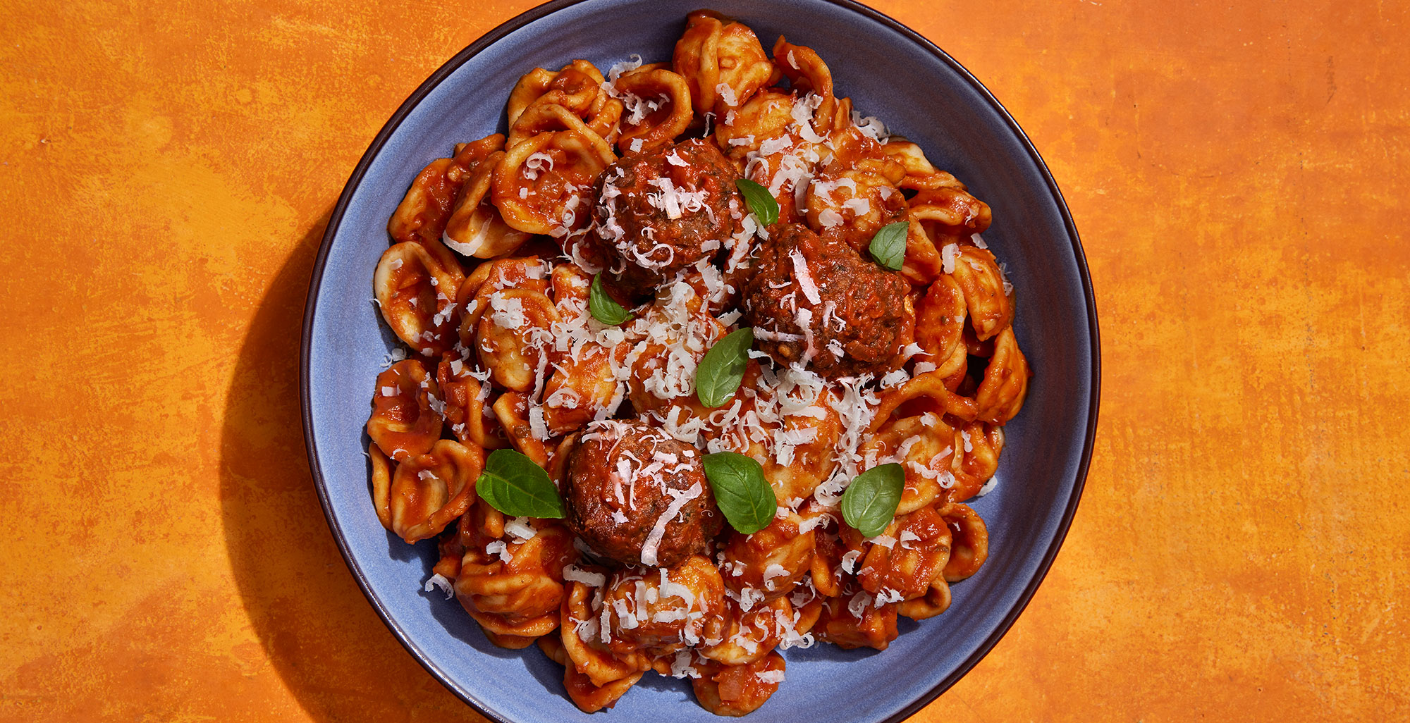 An image of prepared Orecchiette with Roasted Red Pepper and Tomato Sauce made with Pacific Foods® Organic Roasted Red Pepper & Tomato Soup, onion, orecchiette pasta, Italian meatballs, basil and Parmesan.