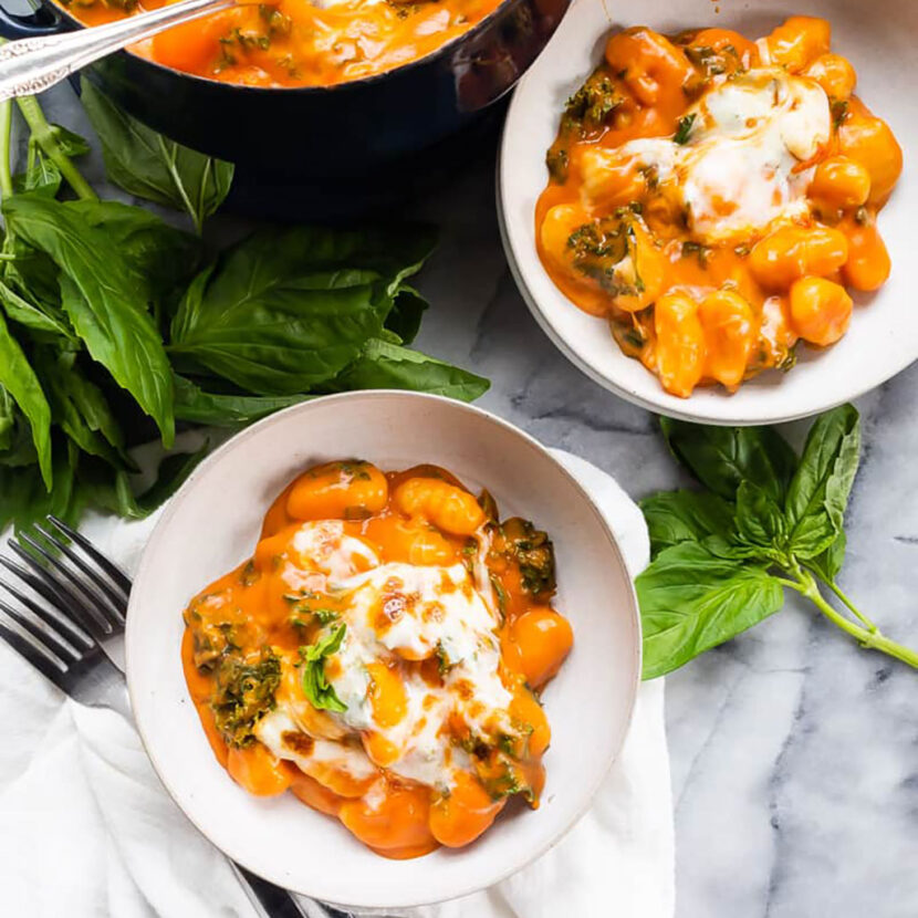 An image of prepared Red Pepper and Tomato Baked Gnocchi made with Pacific Foods® Organic Roasted Red Pepper & Tomato Soup, potato gnocchi, kale, basil and mozzarella cheese.