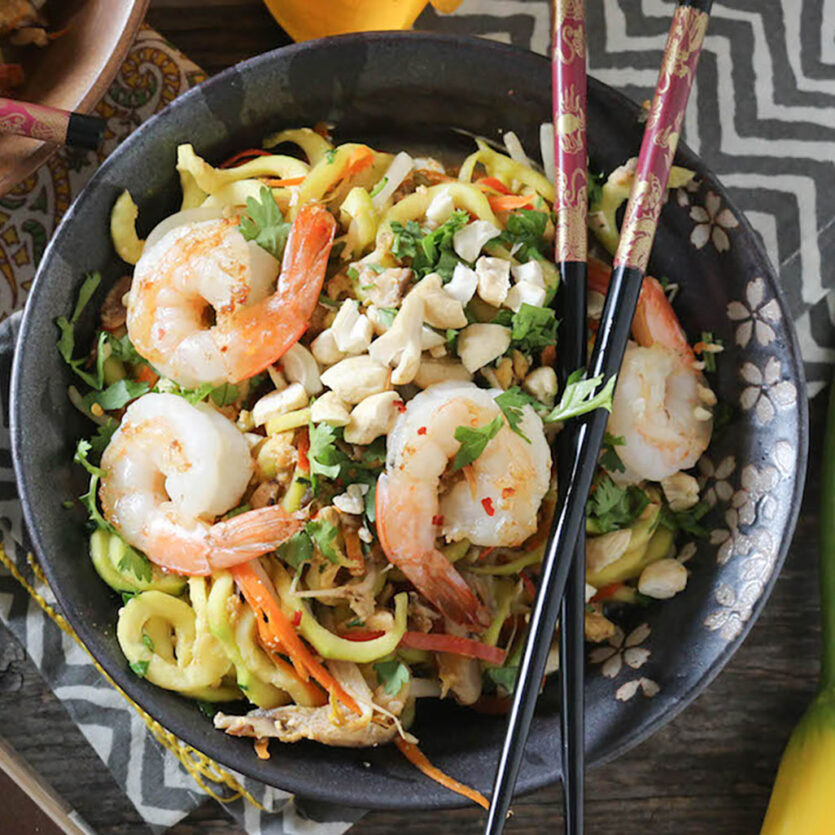 An image of prepared Shrimp & Zucchini Pad Thai made with Pacific Foods® Organic Mushroom Broth, zucchini, shrimp, shittake mushrooms, bell pepper, eggs, bean sprouts, green onion, cashews and cilantro.