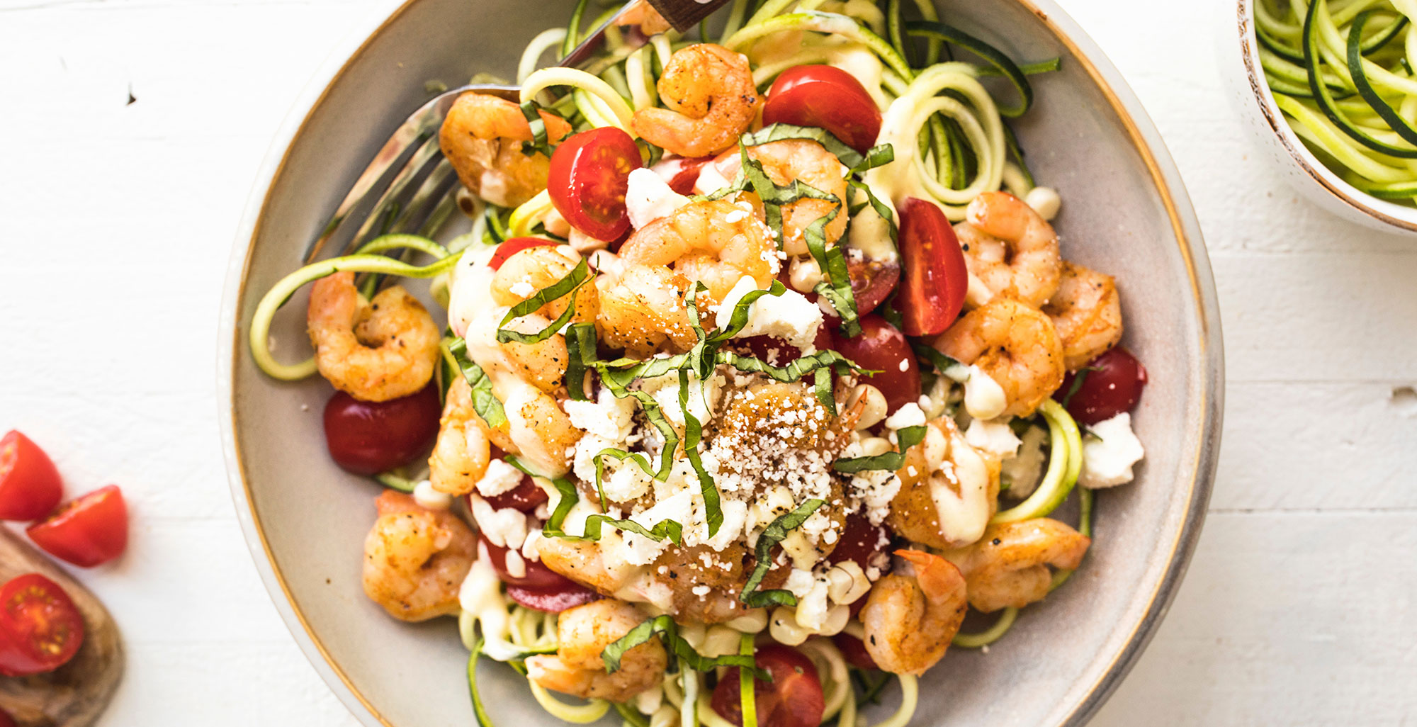 An image of prepared Shrimp Zoodle Bowl made with shrimp, Pacific Foods® Organic Free Range Chicken Broth, yogurt, zucchini, corn, grape tomatoes, feta cheese and basil.