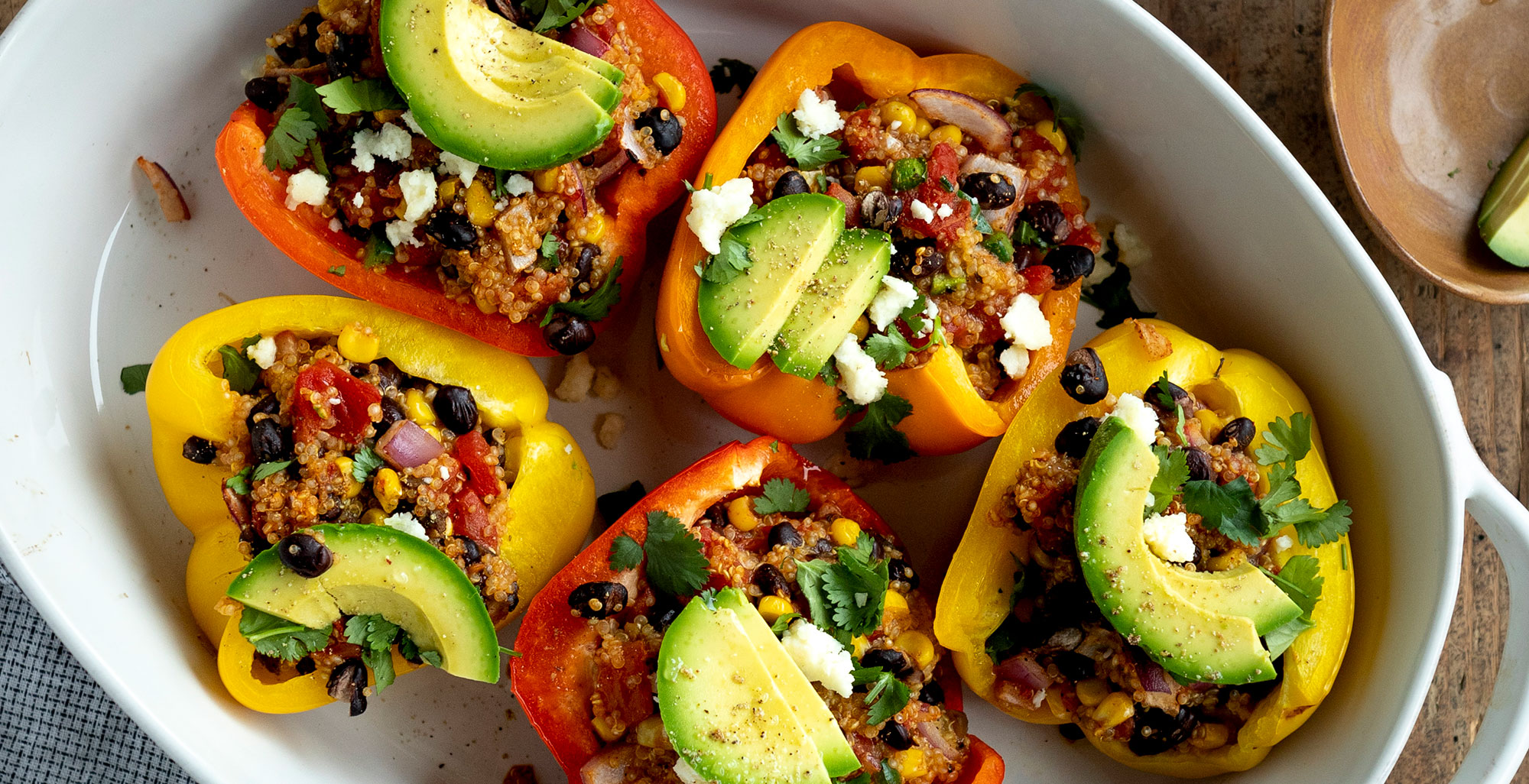 An image of prepared Spicy Stuffed Mexican Peppers made with quinoa, Pacific Foods® Organic Vegetable Broth, Pacific Foods® Organic Cream of Mushroom Condensed Soup, black beans, tomatoes, corn, bell peppers, cilantro, avocado and cotija cheese.