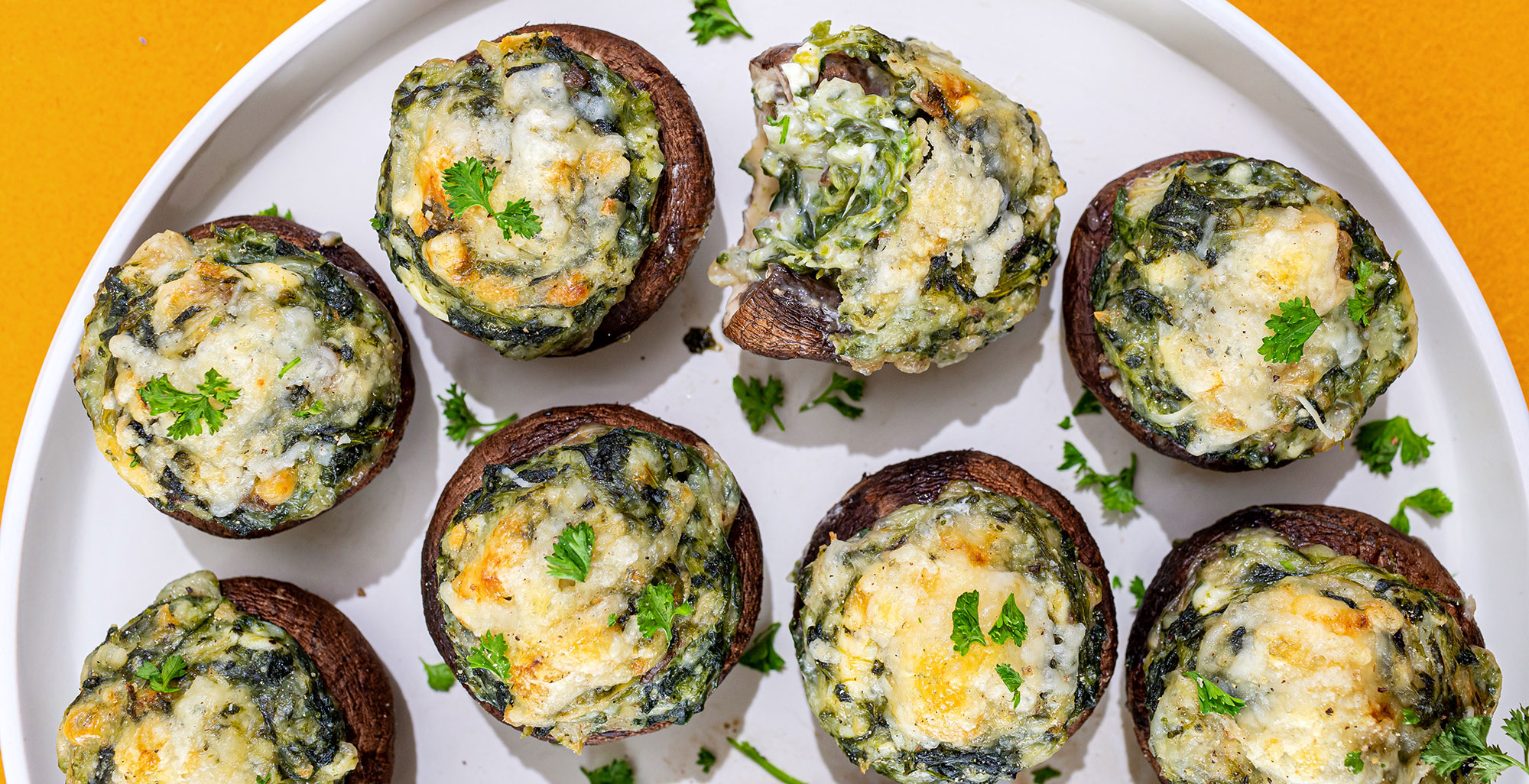 An image of prepared Spinach Artichoke Dip Stuffed Mushrooms made with mushrooms, spinach, Pacific Foods® Organic Cream of Mushroom Condensed Soup, artichoke hearts, Parmesan and cream cheese.