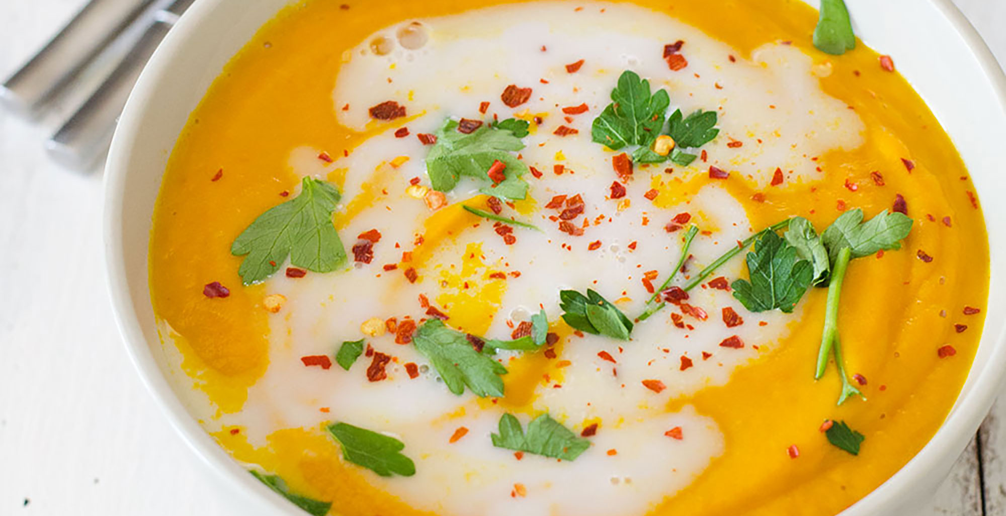 An image of prepared Thai Coconut Carrot Soup made with onion, carrot, Thai red curry paste, Pacific Foods® Organic Vegetable Broth, Pacific Foods® Organic Coconut Plant-Based Beverage, lime juice and cilantro.