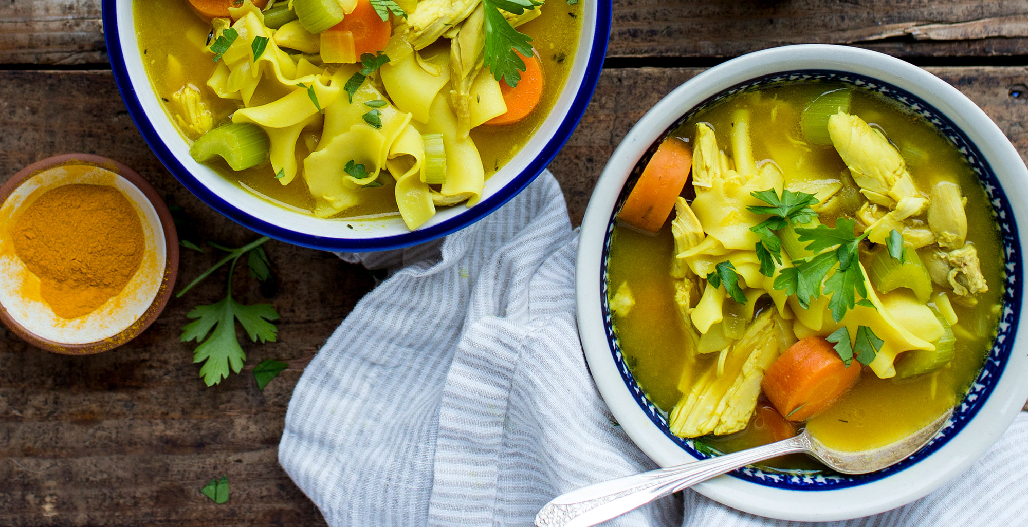An image of prepared Turmeric Chicken Noodle Soup made with turmeric, Pacific Foods® Organic Unsalted Chicken Bone Broth, rotisserie chicken, egg noodles and parsley.