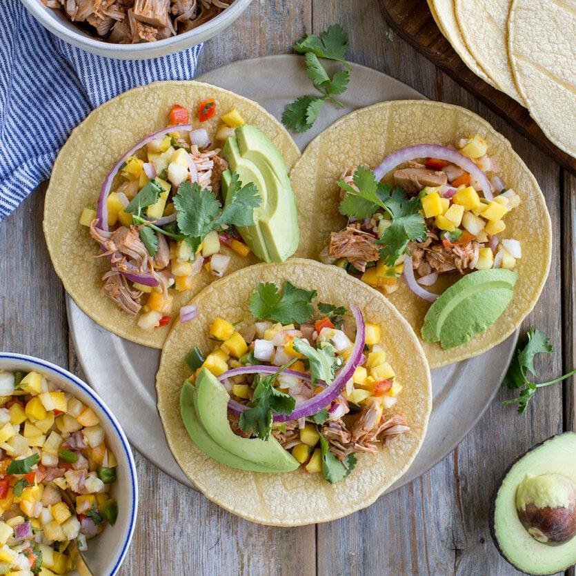 An image of prepared Vegan Instant Pot® Jackfruit Tacos made with Pacific Foods® Organic Vegetable Broth, jackfruit, red onion, corn tortillas, mango, pineapple, peppers, avocado and cilantro.