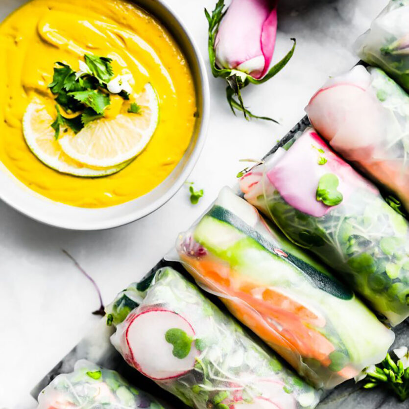 An image of prepared Vegan Spring Rolls with Ginger Curry Dipping Sauce made with Pacific Foods® Organic Cashew Carrot Ginger Soup, cashews, cilantro, rice paper wrapper, carrot, cucumber, zucchini, radish, bean sprouts, cabbage, green onion and cilantro.