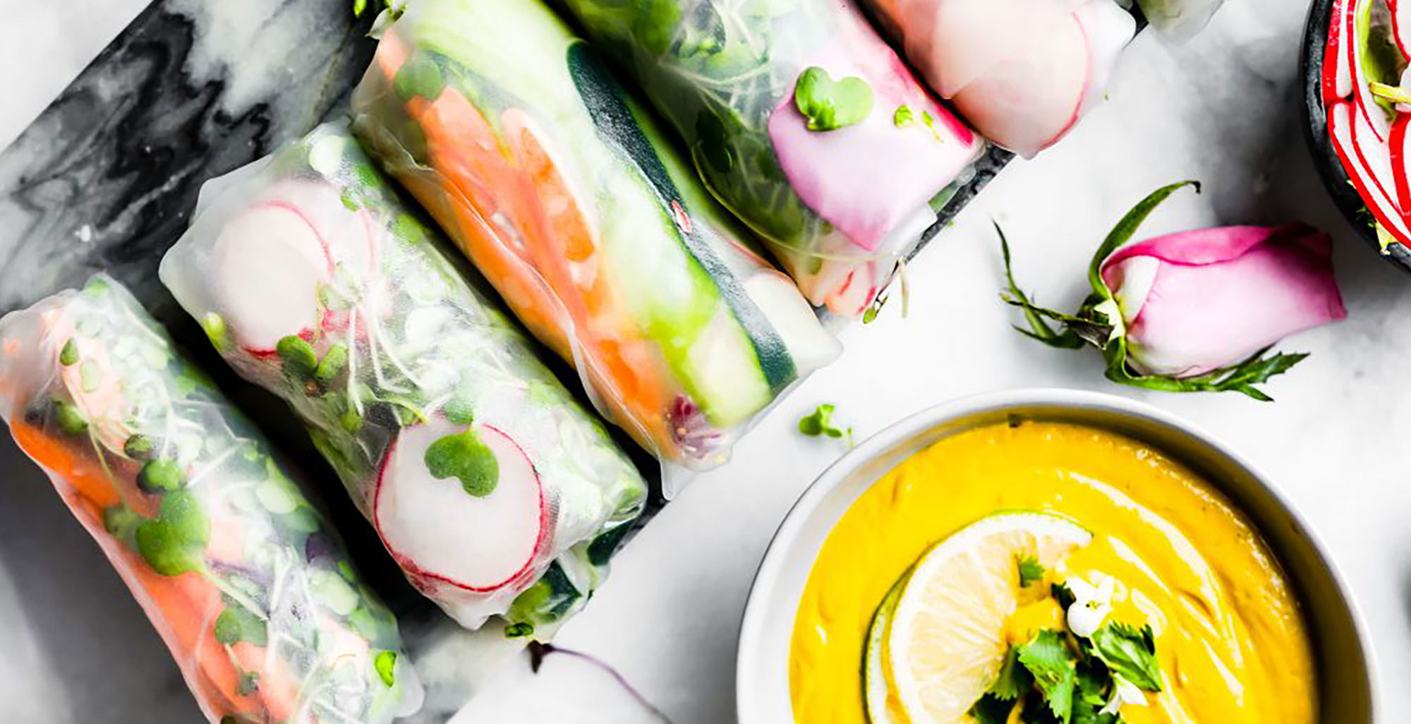 An image of prepared Vegan Spring Rolls with Ginger Curry Dipping Sauce made with Pacific Foods® Organic Cashew Carrot Ginger Soup, cashews, cilantro, rice paper wrapper, carrot, cucumber, zucchini, radish, bean sprouts, cabbage, green onion and cilantro.