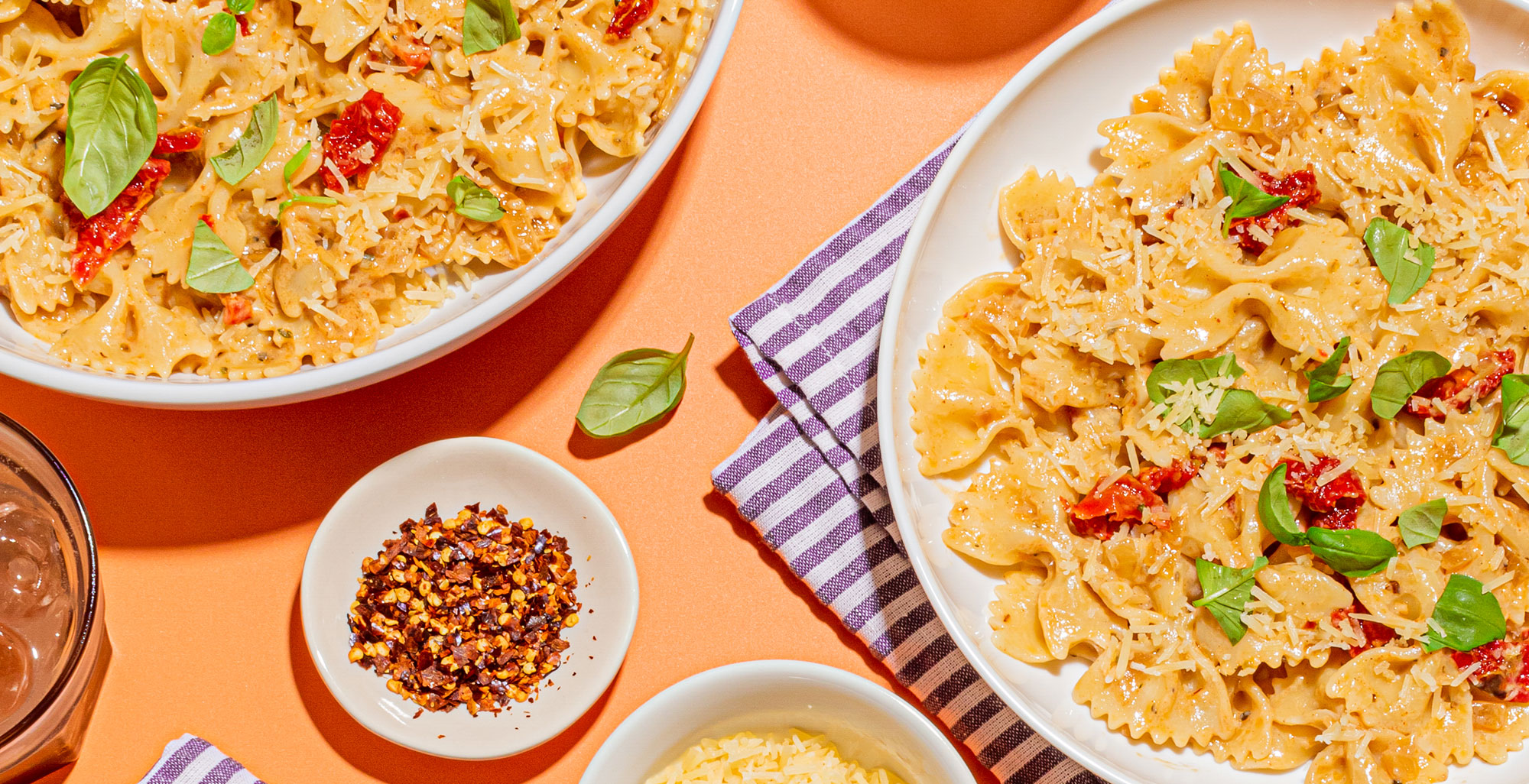An image of prepared Vegan Sun Dried Tomato Cream Pasta made with farfalle, onion, sun-dried tomatoes, Pacific Foods® Hemp Unsweetened Original Beverage and basil.