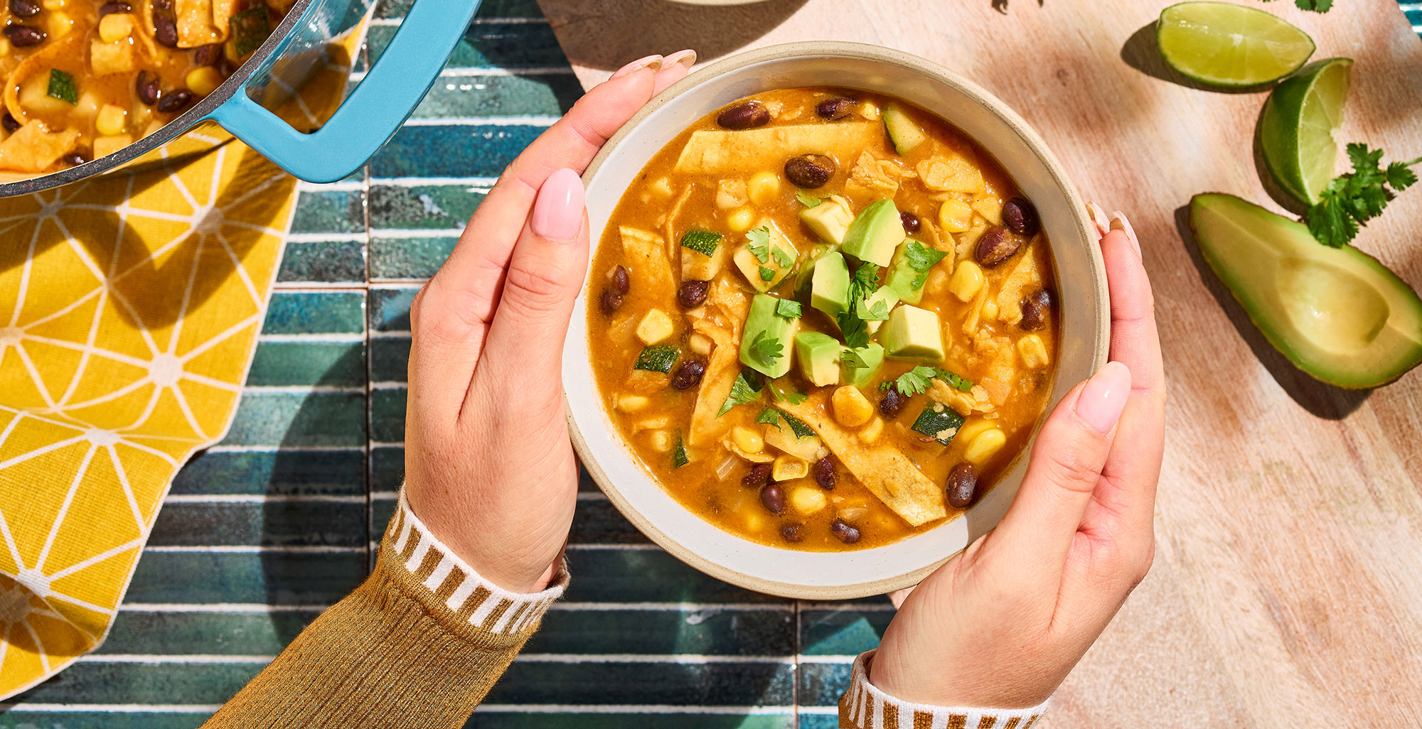 An image of prepared Weeknight Tortilla Soup made with onion, zucchini, corn, black beans, Pacific Foods® Organic Low Sodium Vegetable Broth, Pacific Foods® Organic Creamy Tomato Soup tortillas and avocado.
