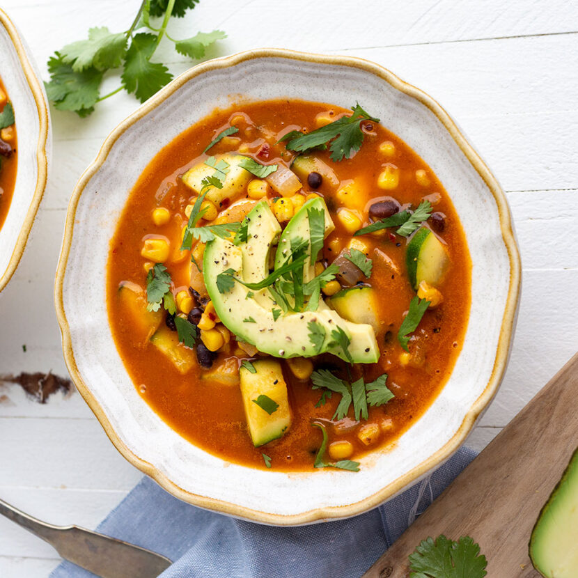 An image of prepared Weeknight Tortilla Soup made with onion, zucchini, corn, black beans, Pacific Foods® Organic Low Sodium Vegetable Broth, Pacific Foods® Organic Creamy Tomato Soup tortillas and avocado.