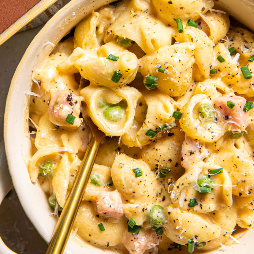 An image of prepared Creamy Stovetop Mac and Cheese with Ham and Peas made with Pacific Foods® Organic Salted Chicken Bone Broth, pasta, peas, evaporated milk, mascarpone, white Cheddar, pepper Jack cheese and ham.