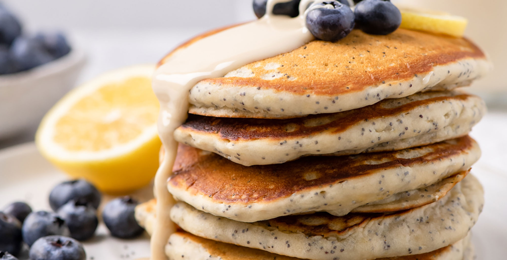 An image of prepared Lemon Poppyseed Pancakes made with lemons, Pacific Foods® Organic Oat Original Beverage, flour, blueberries, maple syrup and poppy seeds.