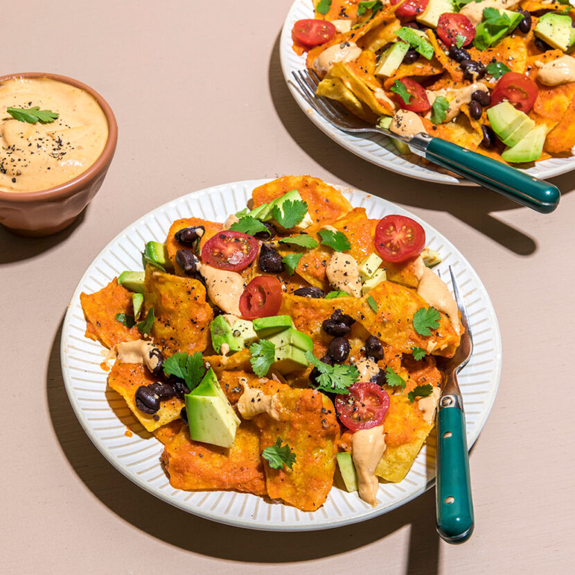 An image of prepared Vegan Chilaquiles made with cashews, nutritional yeast, chipotles, onion, diced fire roasted tomatoes, Pacific Foods® Organic Vegetable Broth, tortilla chips, avocado, pinto beans, cherry tomatoes and cilantro.