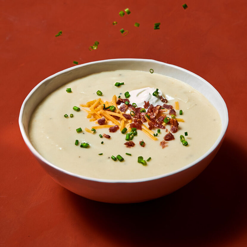 An image of prepared Life-Changing Leftover Mashed Potato Soup made with whole milk, Pacific Foods® Organic Low Sodium Chicken Broth, mashed potatoes, Cheddar cheese, green onion and bacon.