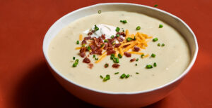 An image of prepared Leftover Mashed Potato Soup made with whole milk, Pacific Foods® Organic Low Sodium Chicken Broth, mashed potatoes, Cheddar cheese, green onion and bacon.