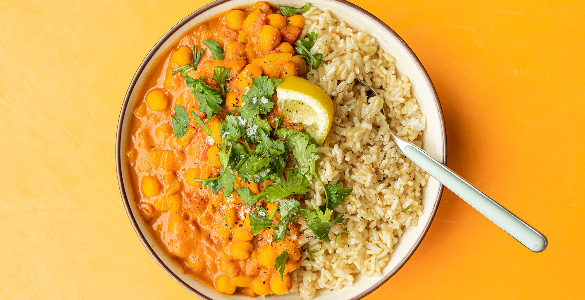 An image of prepared Slow-Cooker Butternut Chickpea Curry made with curry powder, crushed tomatoes, chickpeas, Pacific Foods® Organic Creamy Butternut Squash Soup, brown rice, cilantro and lemon.