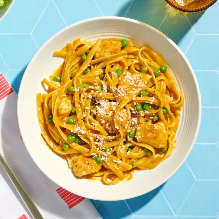 An image of prepared One-Pot Butternut Squash Alfredo with Chicken & Peas made with chicken, Pacific Foods® Organic Creamy Butternut Squash Soup, Pacific Foods® Organic Free Range Chicken Broth, fettuccine, green peas and Parmesan.