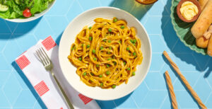 An image of prepared Vegan One Pot Butternut Alfredo made with Pacific Foods® Organic Creamy Butternut Squash Soup, Pacific Foods® Organic Vegetable Broth, fettuccine pasta and peas.