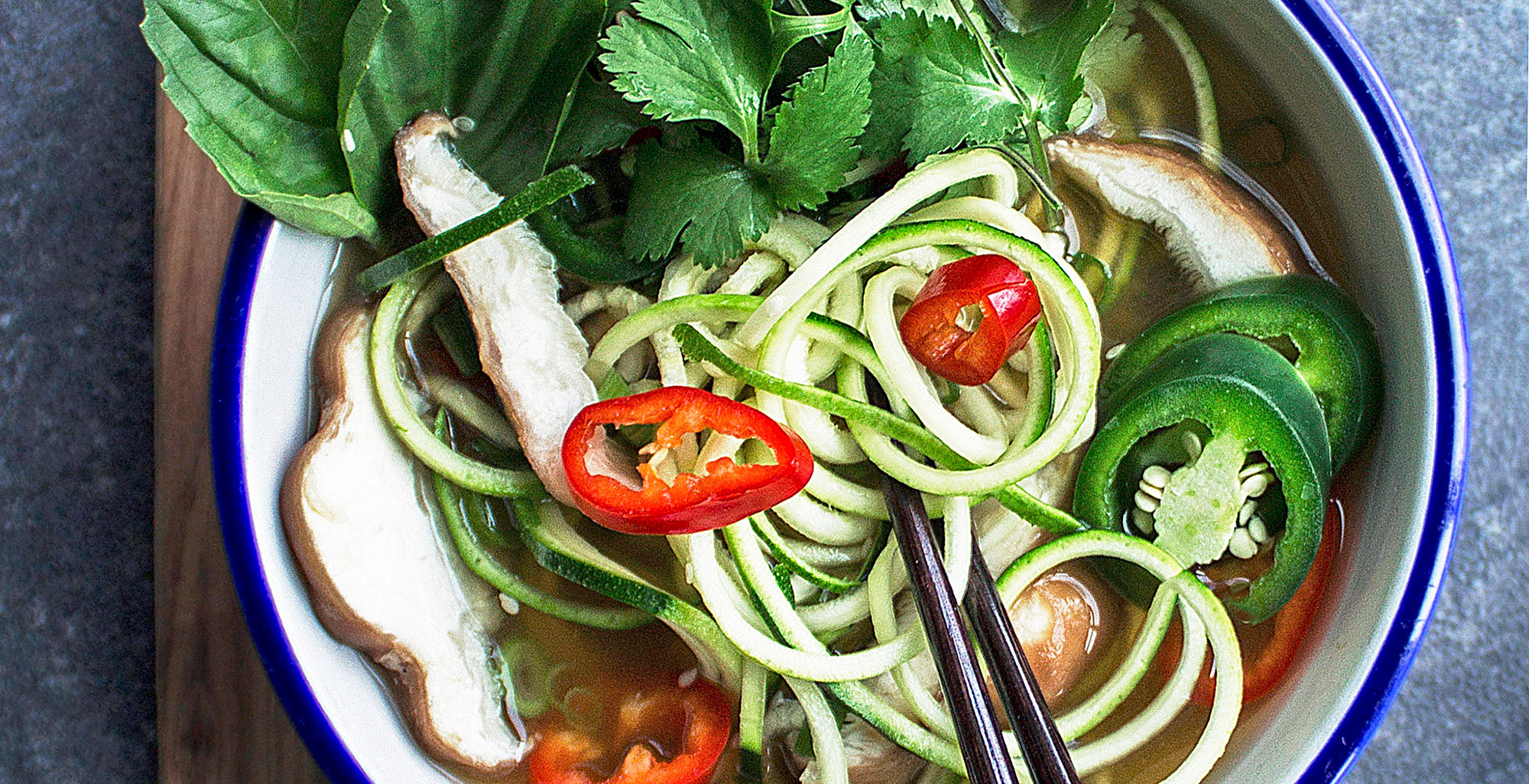 An image of prepared Pho Zucchini Noodle Soup made with Pacific Foods® Organic Mushroom Broth, garlic, lemongrass, ginger, mushrooms, jalapeño peppers, zucchini, basil and cilantro.