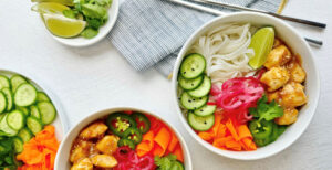 An image of prepared Gluten-Free Banh Mi Chicken Bowls made with rice noodles, onion, chicken, Pacific Foods® Condensed Cream of Celery Soup, carrot, cucumber and cilantro.