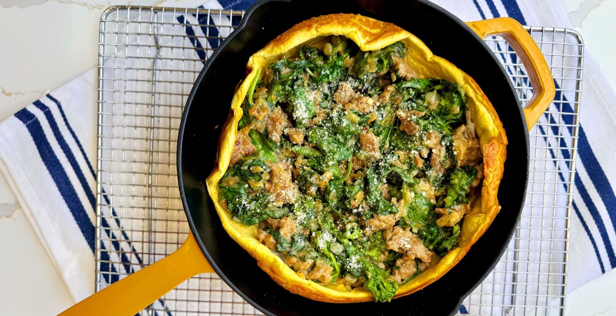 An image of prepared Savory Sausage & Broccoli Rabe Dutch Baby made with Pacific Foods® Condensed Cream of Roasted Garlic and Herb Soup, turkey sausage, broccoli rabe, spinach and onion.