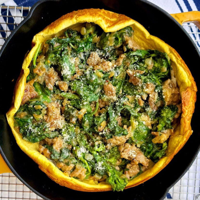 An image of prepared Savory Sausage & Broccoli Rabe Dutch Baby made with Pacific Foods® Condensed Cream of Roasted Garlic and Herb Soup, turkey sausage, broccoli rabe, spinach and onion.